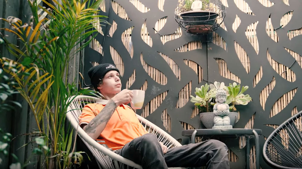 A young man sitting in a chair and drinking coffee in his garden