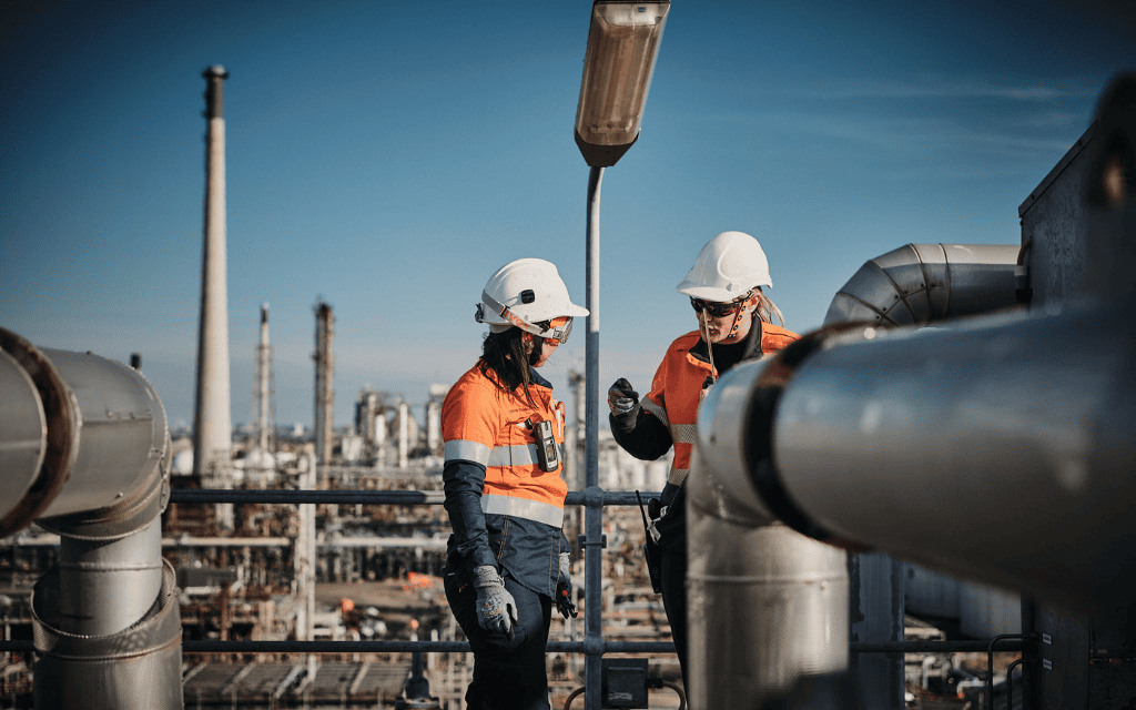 Two women wearing hi-vis clothing and protective gear talking