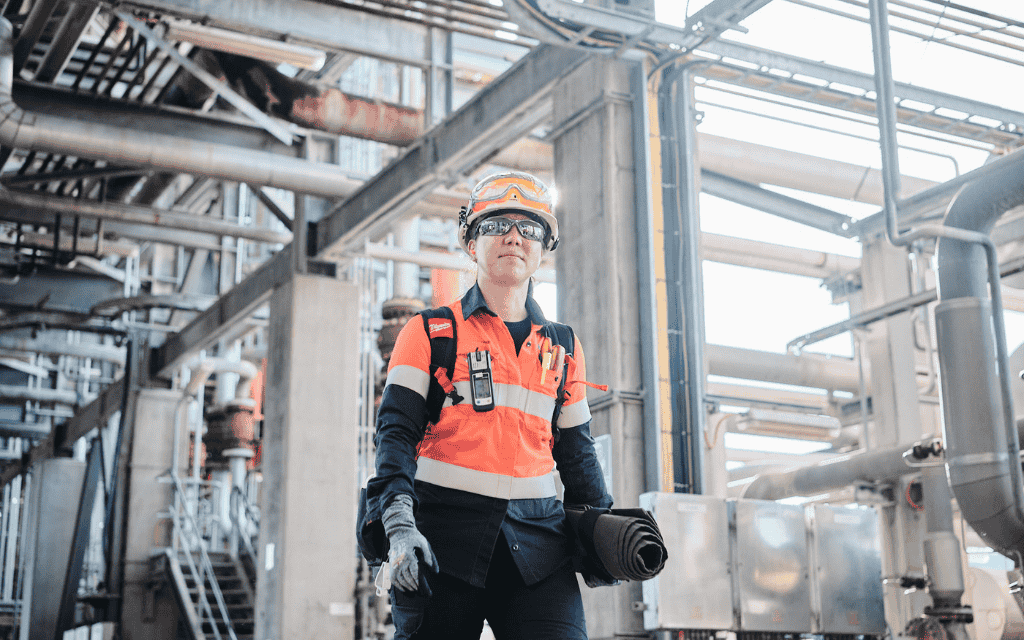 Woman wearing a high vis vest, hard hat and safety glasses walking in a factory