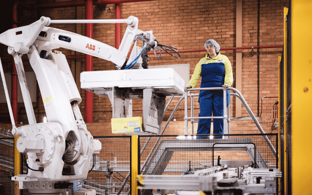 Woman standing on a ladder overlooking machinery in a factory