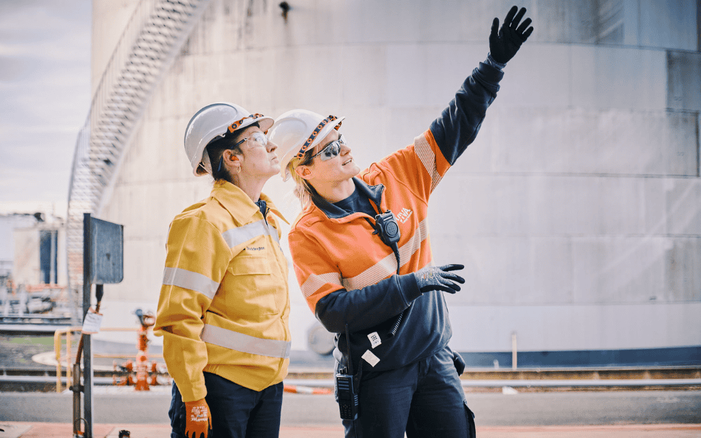 Two women wearing protective clothing talking and looking up