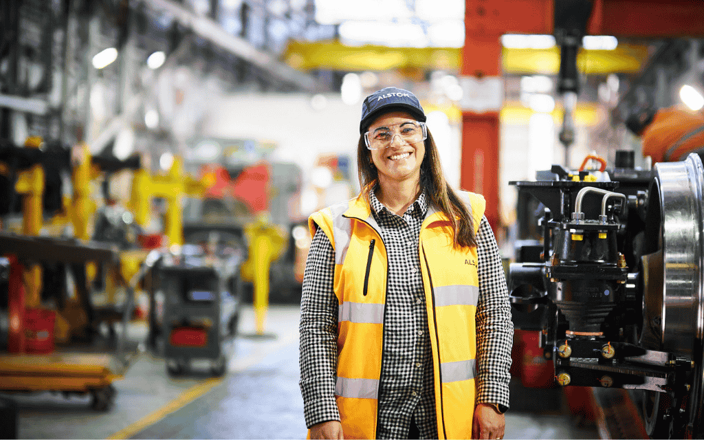 Woman smiling at the camera wearing safety glasses and a hi-vis vest