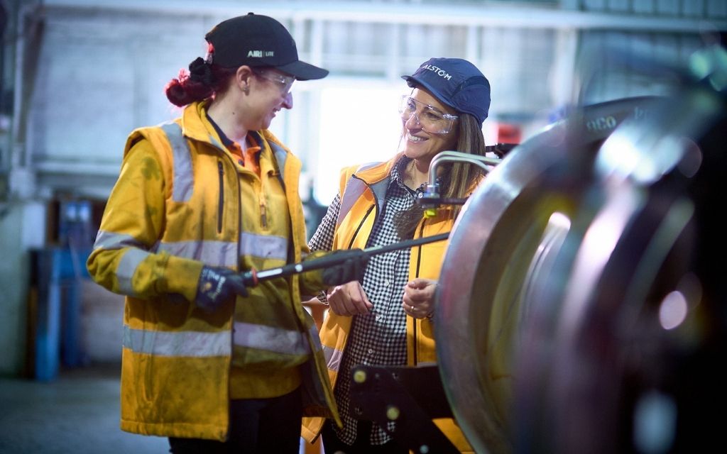 Two women wearing hi-vis working on machinery