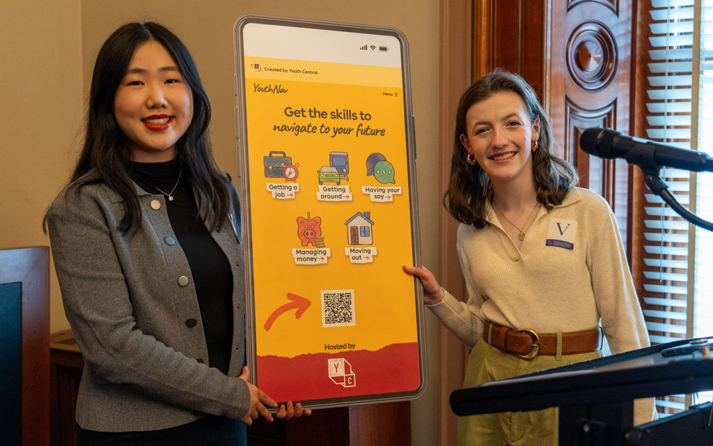 Two women holding a large cardboard mobile phone.