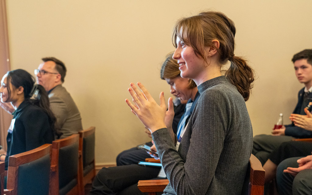 A woman sitting in the audience clapping.