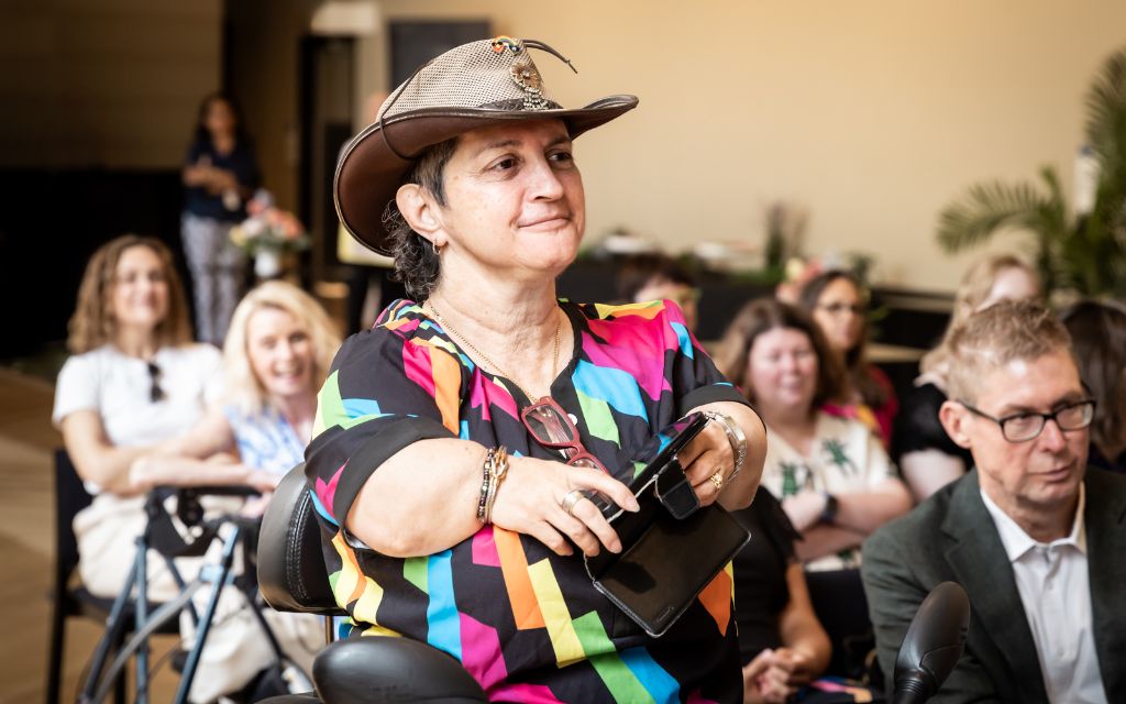 A women smiling and watching an awards ceremony.